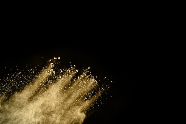 Golden powder explosion on black background. Freeze motion. 