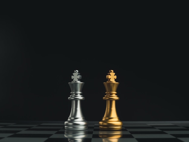 A golden queen chess piece and a silver queen chess piece are standing together on a chessboard on dark background. Leadership, partnership, competitor, confrontation, and business strategy concept.