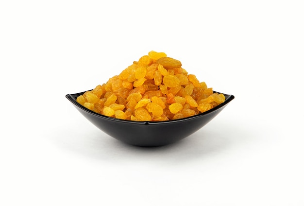 Golden raisins in a dark plate isolated on a white background