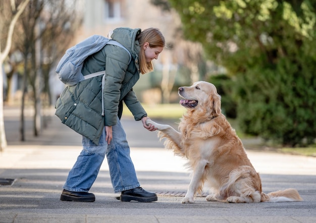 Photo golden retriever gives paw to its young girl owner during winter walk with dog