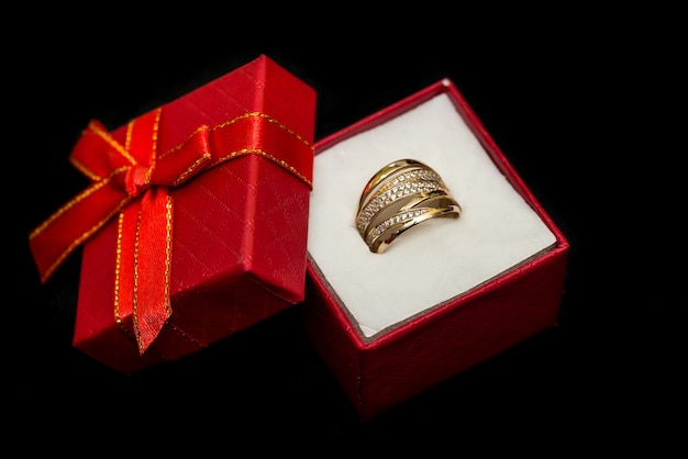 Золотое кольцо в красной подарочной коробке, изолированное на черном
