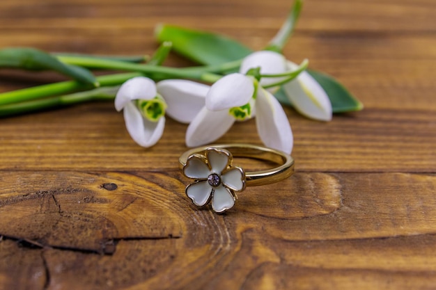 Golden ring and snowdrops on wooden background