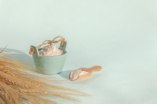 Golden rye ears and bowls of flour on light background Dry yellow cereals spikelets with shadow closeup copy space