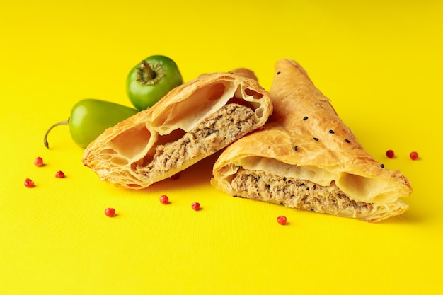 Golden samsa with ingredients on yellow background