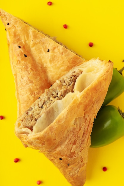 Golden samsa with ingredients on yellow background