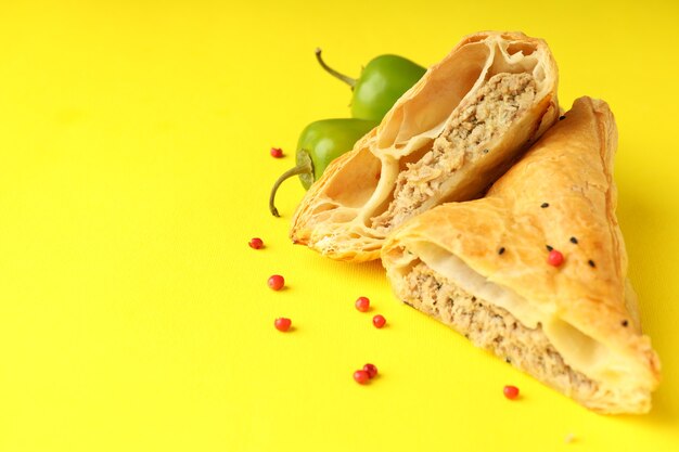 Golden samsa with ingredients on yellow background