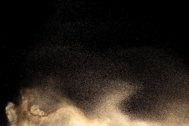 Golden sand explosion on black background