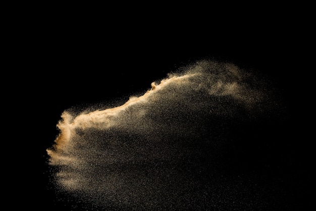 Golden sand explosion isolated on black background. Abstract sand cloud.