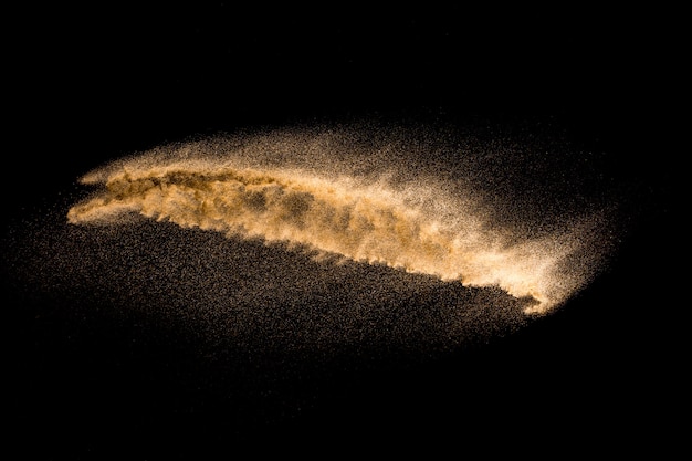 Golden sand explosion isolated on black background. Abstract sand cloud.