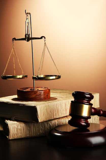 Golden scales of justice gavel and books on brown background