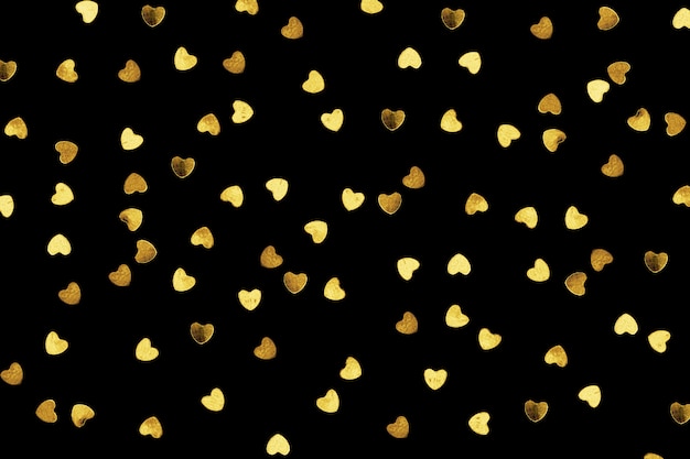Photo golden shiny confetti hearts isolated on black