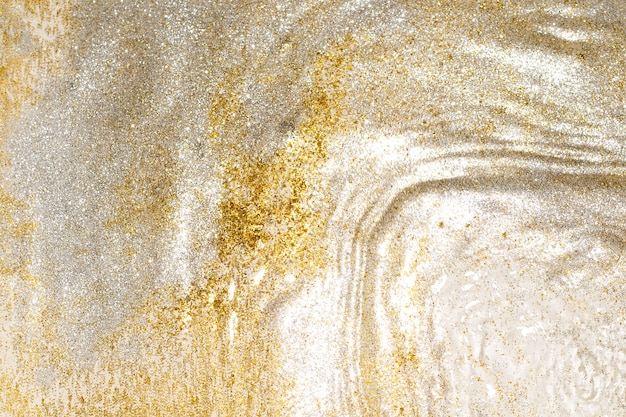 Golden and silver sparkles in water. Glitter and liquid texture. Abstract background with golden an silver particles. Shining celebration background. Festive backdrop for your projects.