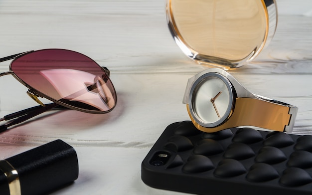 Golden and silver watch and sunglasses on white table