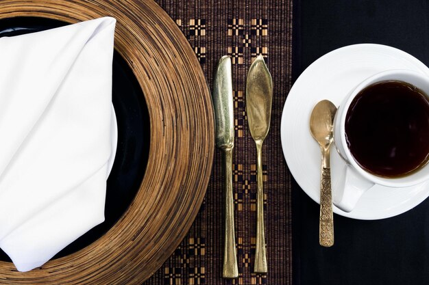 Photo golden silverware laid on a table with a plate and a cup