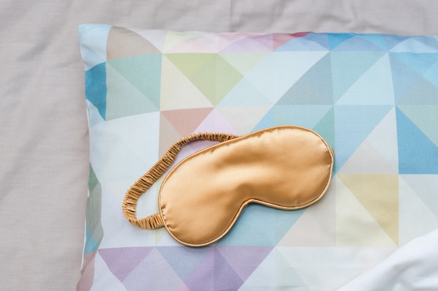 Golden sleeping eye mask on the bed