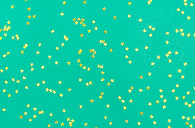 Golden small star sprinkles on mentol green. Festive holiday. flat lay.  