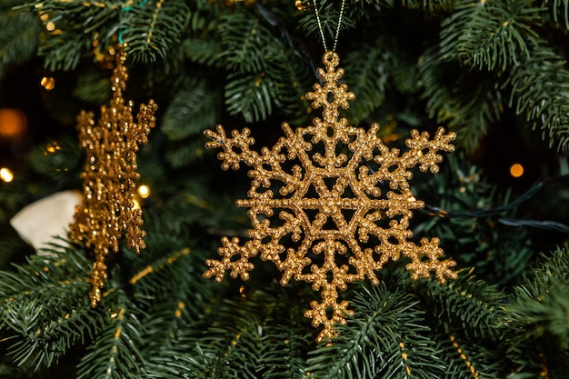 Golden snowflake on a Christmas tree New year decoration Christmas holidays concept New year background with gold snowflake on a Christmas tree