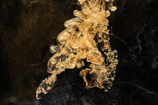 Golden sparkling abstract background luxury black smoke acrylic\
paint underwater explosion cosmic swirling ink