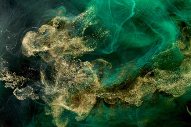 Golden sparkling abstract background luxury green smoke acrylic paint underwater explosion cosmic swirling ink