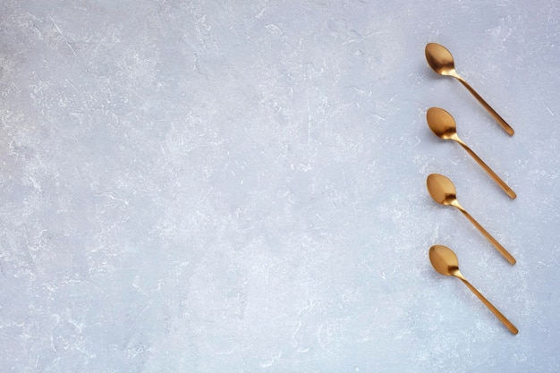 Cucchiai dorati su sfondo grigio spazio flatlay per la creazione di un elenco o di un piano