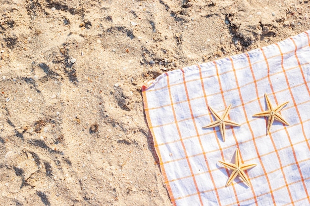 Golden starfish on a bedspread on a sandy beach Top view flat lay