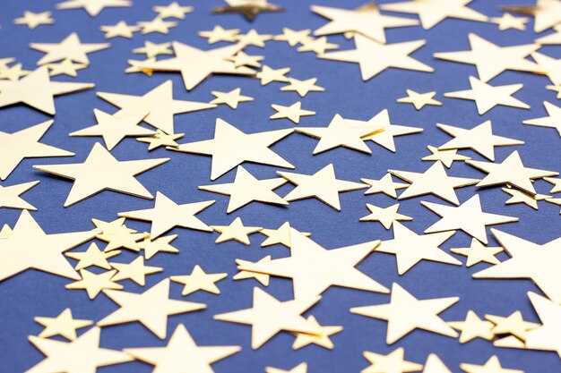 Golden stars glitter on blue background selective focus Festive holiday pastel backdrop