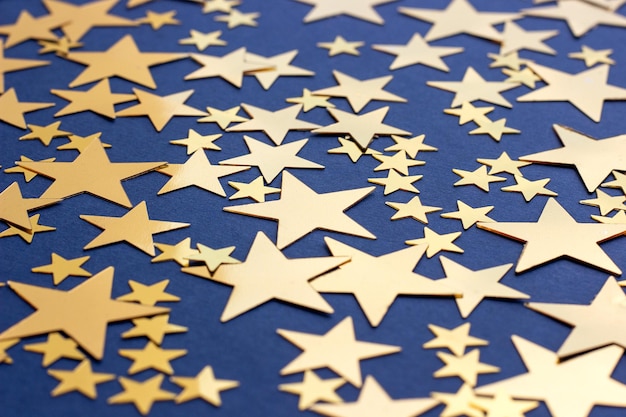 Golden stars glitter on blue background selective focus Festive holiday pastel backdrop