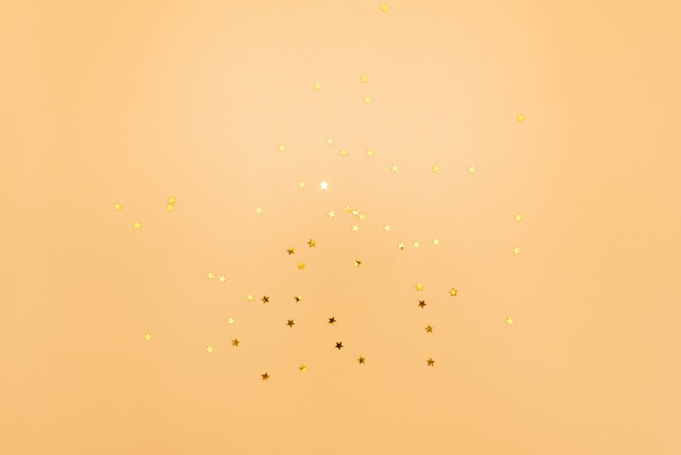 Golden stars glitter on pink background. festive holiday pastel backdrop.