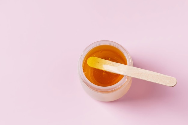 Golden sugar paste or wax for epilation on pink background. Sugaring and depilation