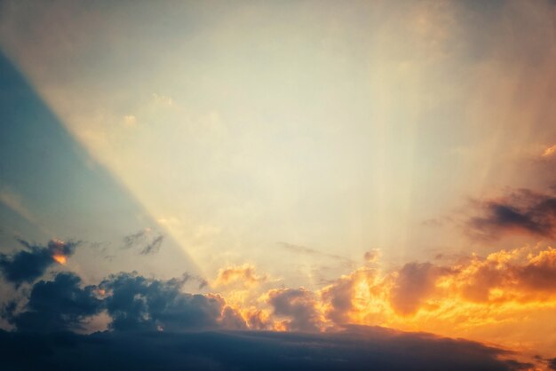 青い空に沈む夕日、明るい太陽光線が雲を通過します