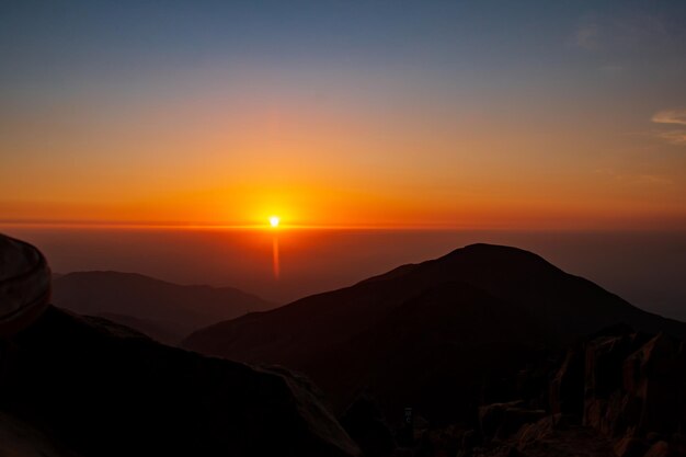Foto tramonto dorato tra nuvole e montagne il sole che tramonta all'orizzonte