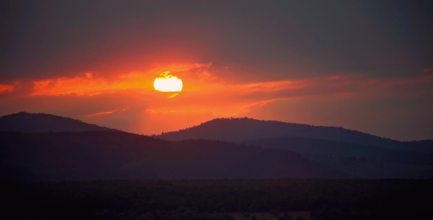 Golden sunset among cloudy twilight sky in the mountains