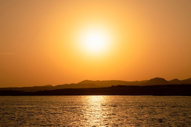シャルムエルシェイクエジプトからの山の壮大な景色の後ろに隠れている紅海の太陽に沈む黄金の夕日