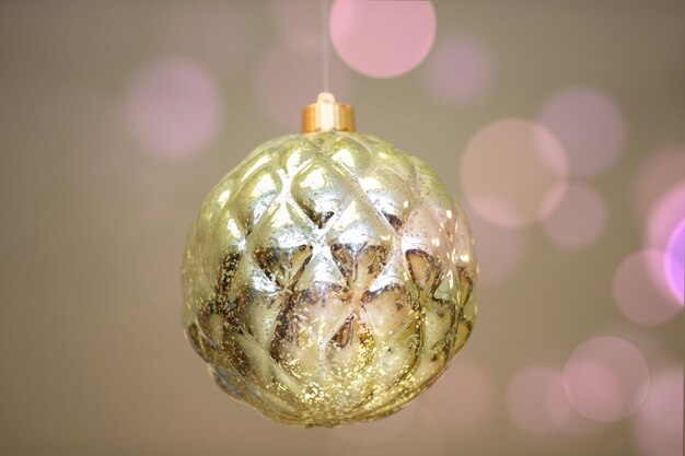 ピンクのボケスポットの背景に黄金のおもちゃのクリスマスボール