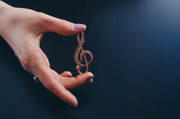 Golden violin key in the hands of women. jewellery: brooch and rings. copy 