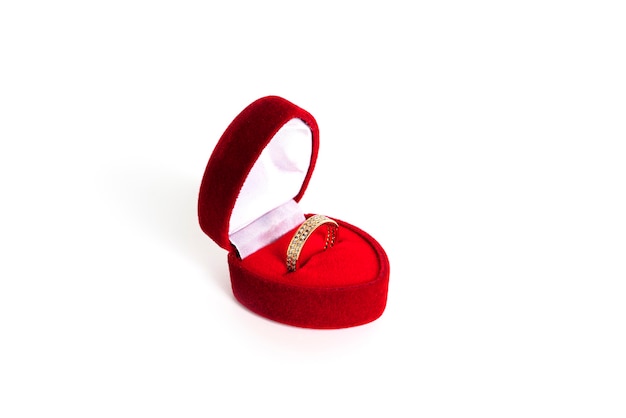 흰색 배경에 격리된 빨간색 하트 모양의 보석 상자에 황금 결혼 반지가 있습니다. 고품질 사진