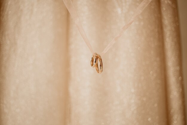 Golden wedding rings hanging on a ribbon