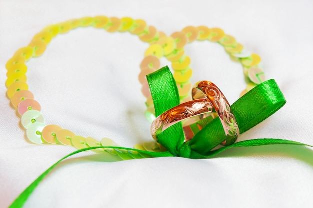 Golden wedding rings with ornament on silk with green ribbon.