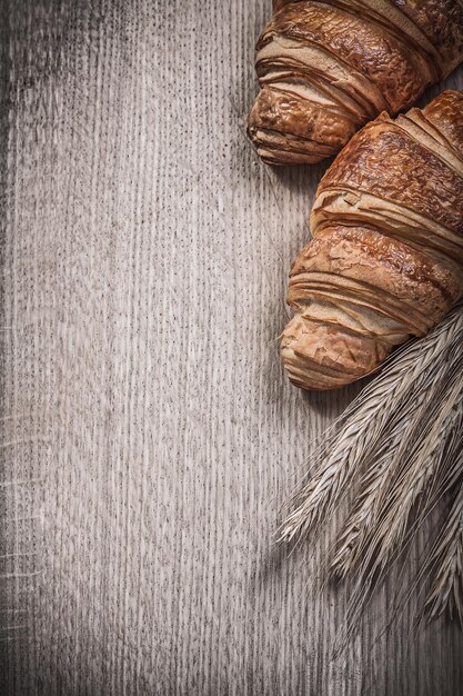 Golden wheat rye ears baked croissants on wooden board