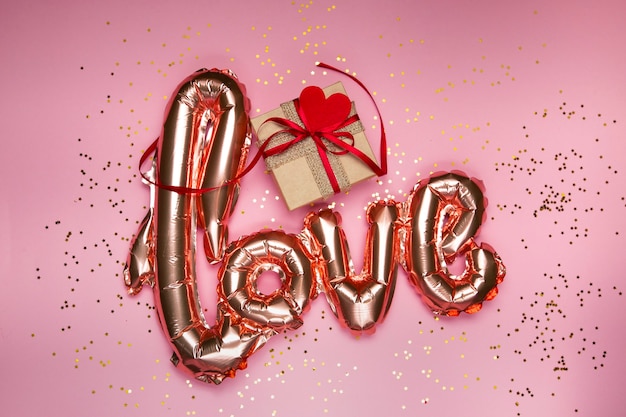 golden word love with gift box on pink background