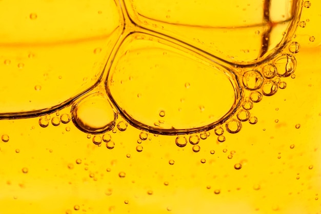 Фото Золотые желтые абстрактные масляные пузырьки или фоновый сыворотка лица масляные и водяные пузарки макрофотография