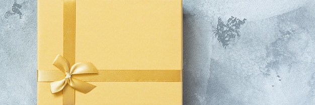 Photo golden yellow box gift on a gray concrete background