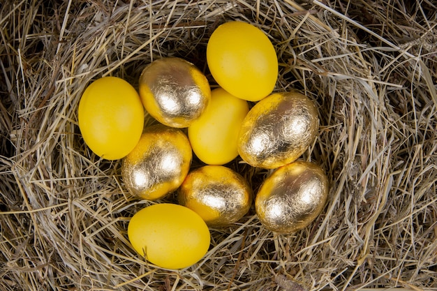 Photo golden and yellow eggs in a nest top view. concept easter.