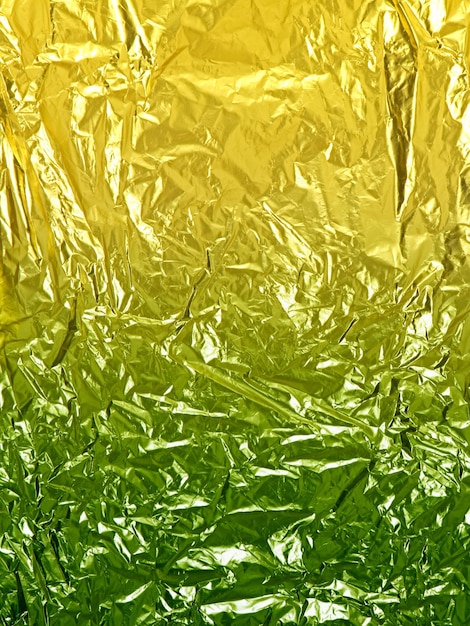 Golden yellow green shiny wrinkled foil paper sheet texture and background