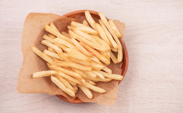 Golden yummy deep french fries on kraft baking sheet paper and\
serving tray to eat with ketchup and yellow mustard top view\
lifestyle