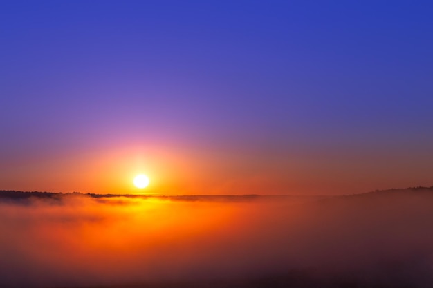 ミニマルな構成で雲のない霧の上のゴールデンブルーの夏の日の出