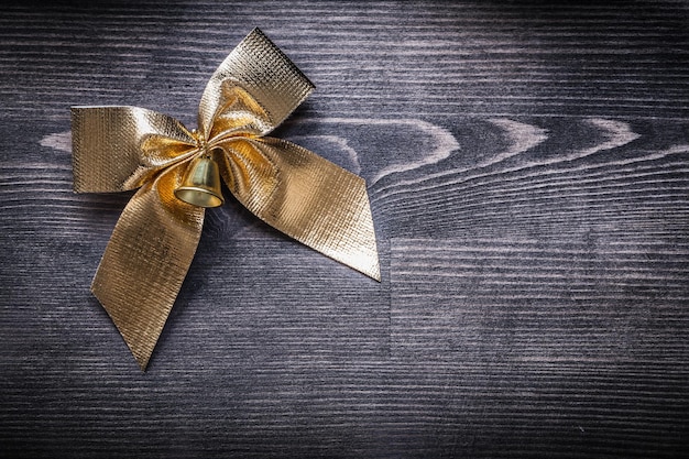 Goldshining bow with bell on wooden board holiday concept