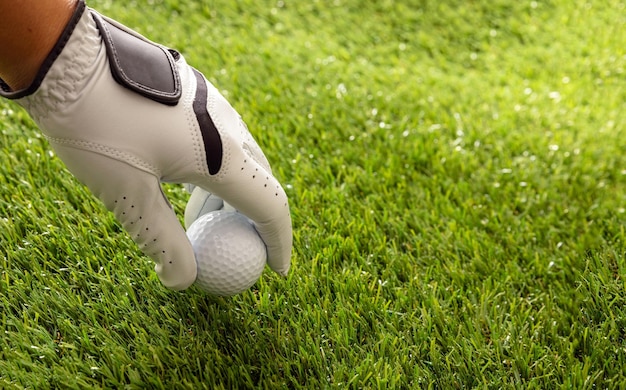 Мяч для гольфа в перчатке в руке зеленый участок газон фон крупный вид