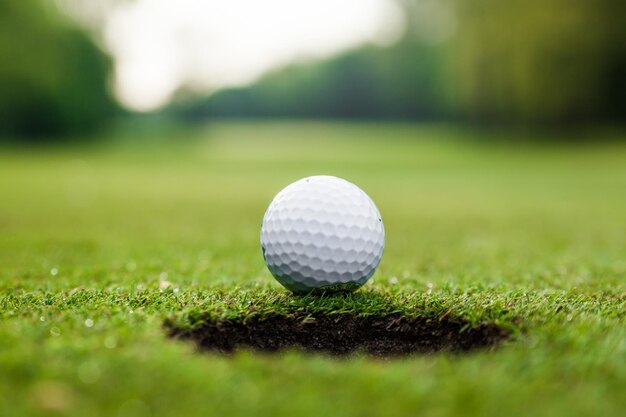 Golf ball on green meadow golf ball on lip of cup