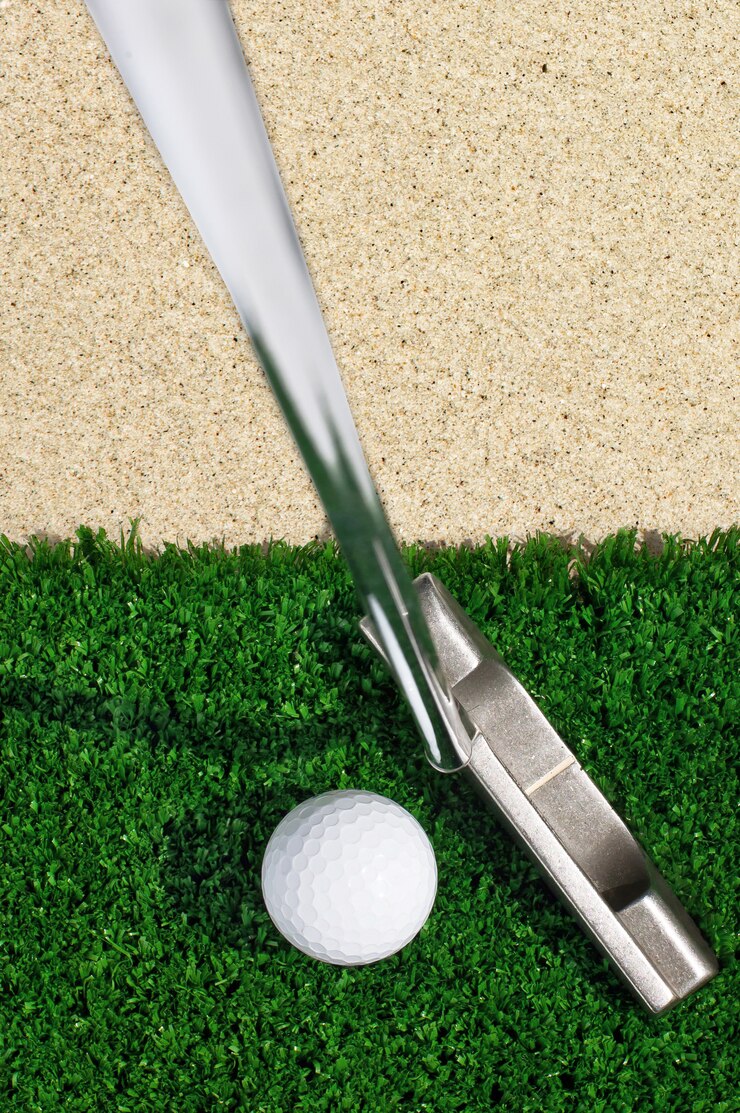 Golf ball and putter on green grass 